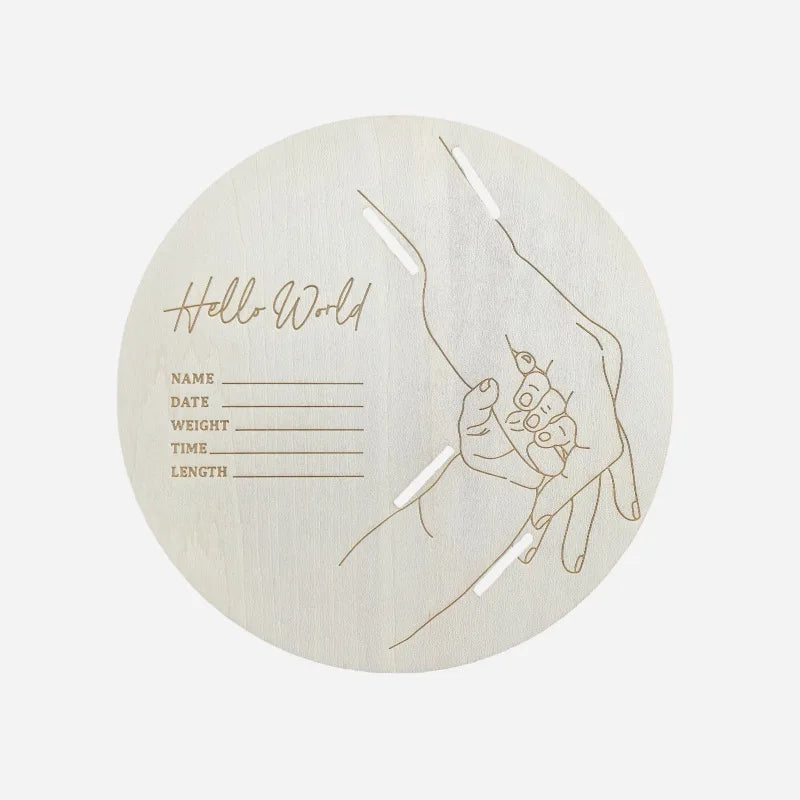 Round natural wood birth announcement sign with "Hello World," baby stats, and engraved parent-child hands.