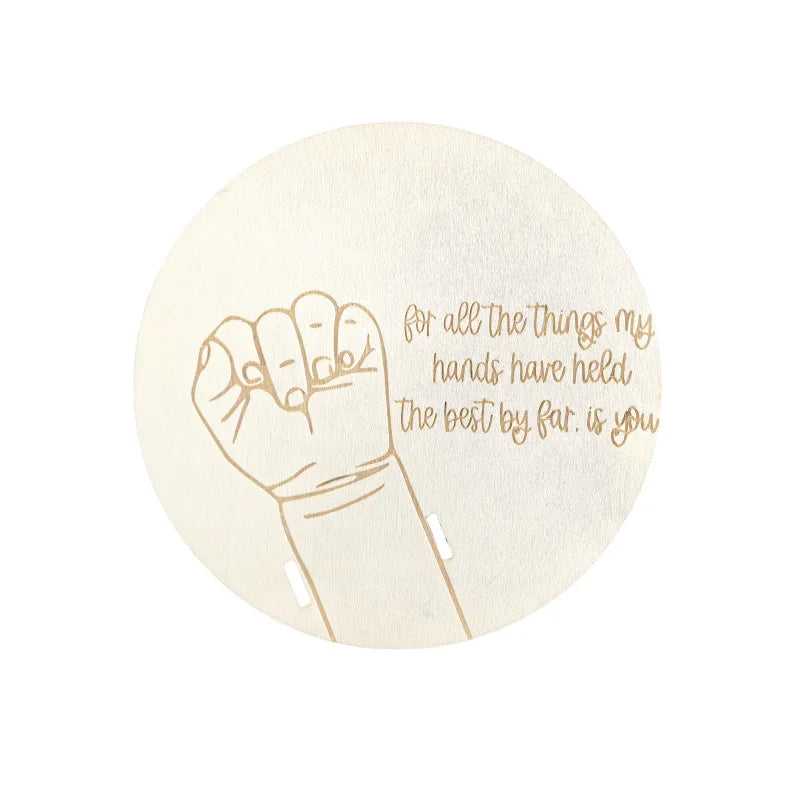 Round wooden birth keepsake with engraved baby hand and "for all the things my hands have held the best by far. is you" quote.