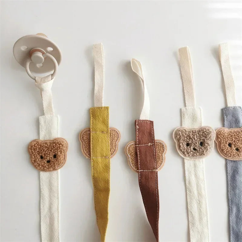 Assortment of five cotton pacifier clips with embroidered teddy bears in various colors.