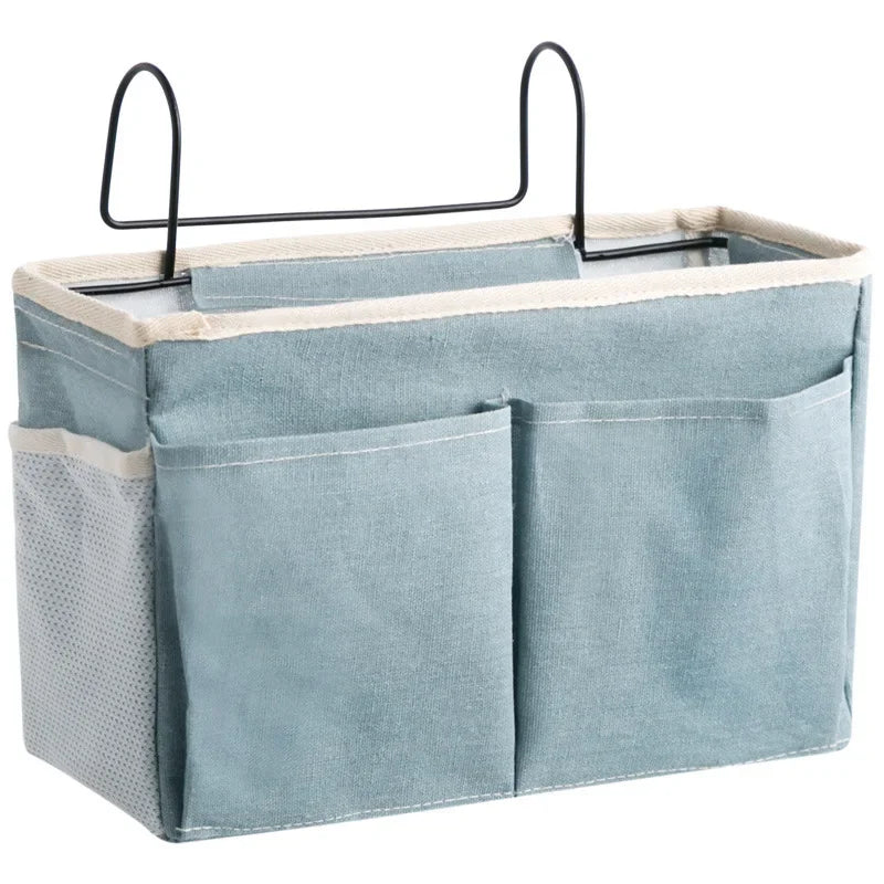 Light blue cotton multi-pocket bedside organizer with a black metal hook for baby essentials.