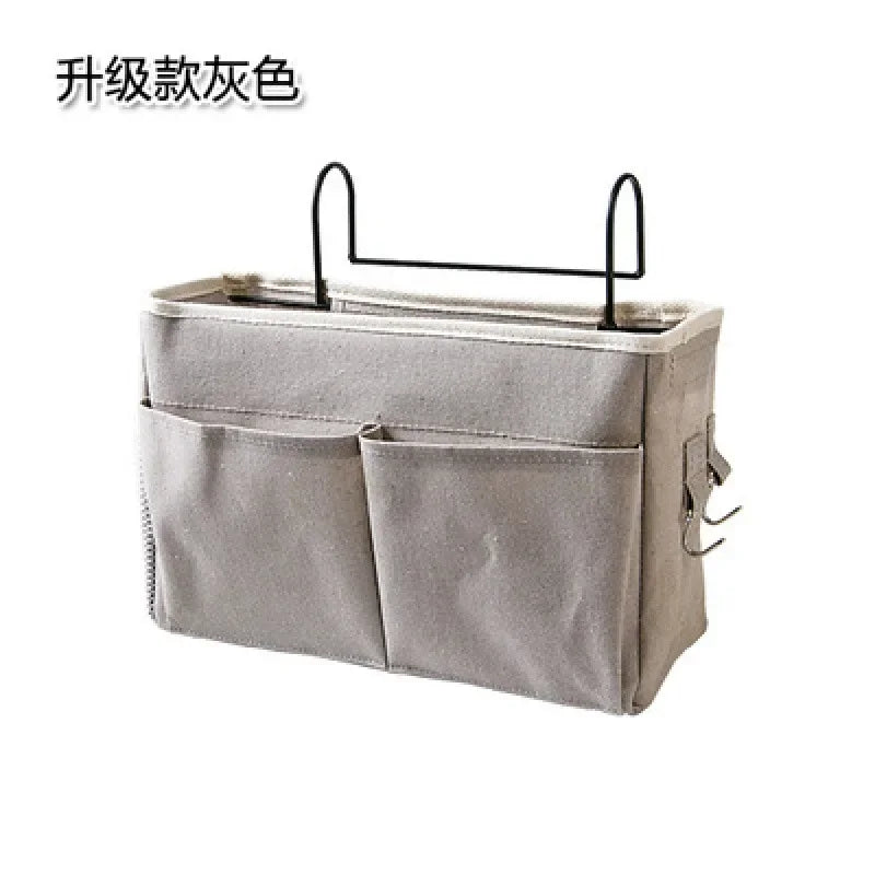 Gray multi-pocket cotton blend bedside caddy organizer with black metal hooks for baby cribs.