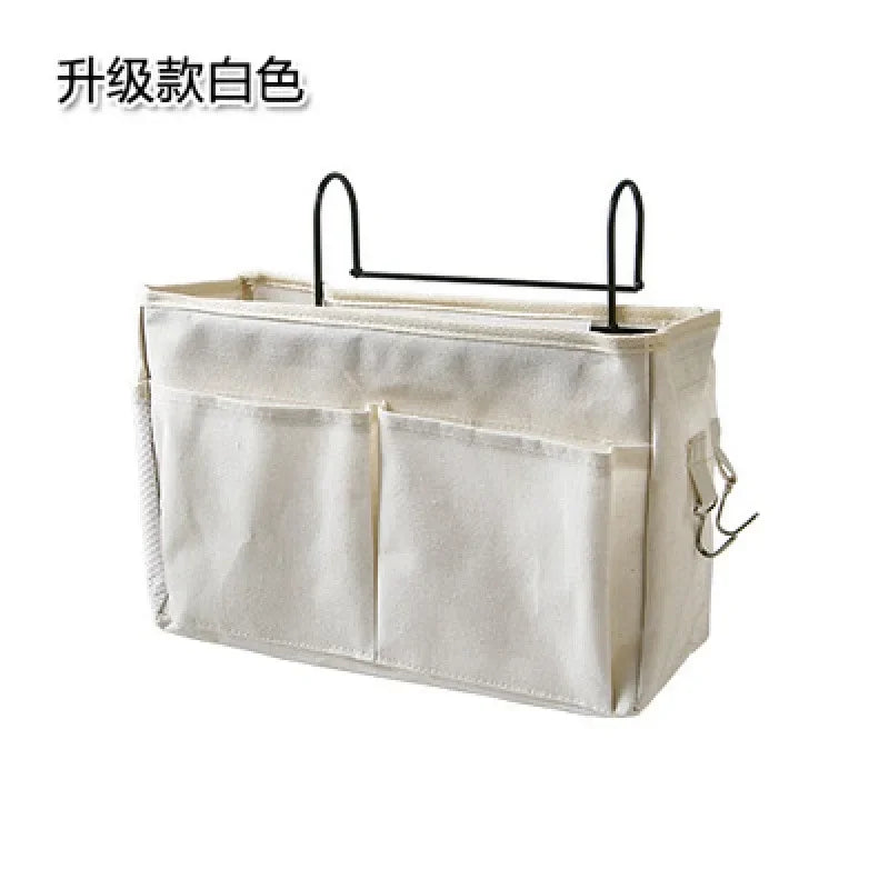 White multi-compartment cotton fabric hanging storage organizer for baby cribs with black metal hooks.