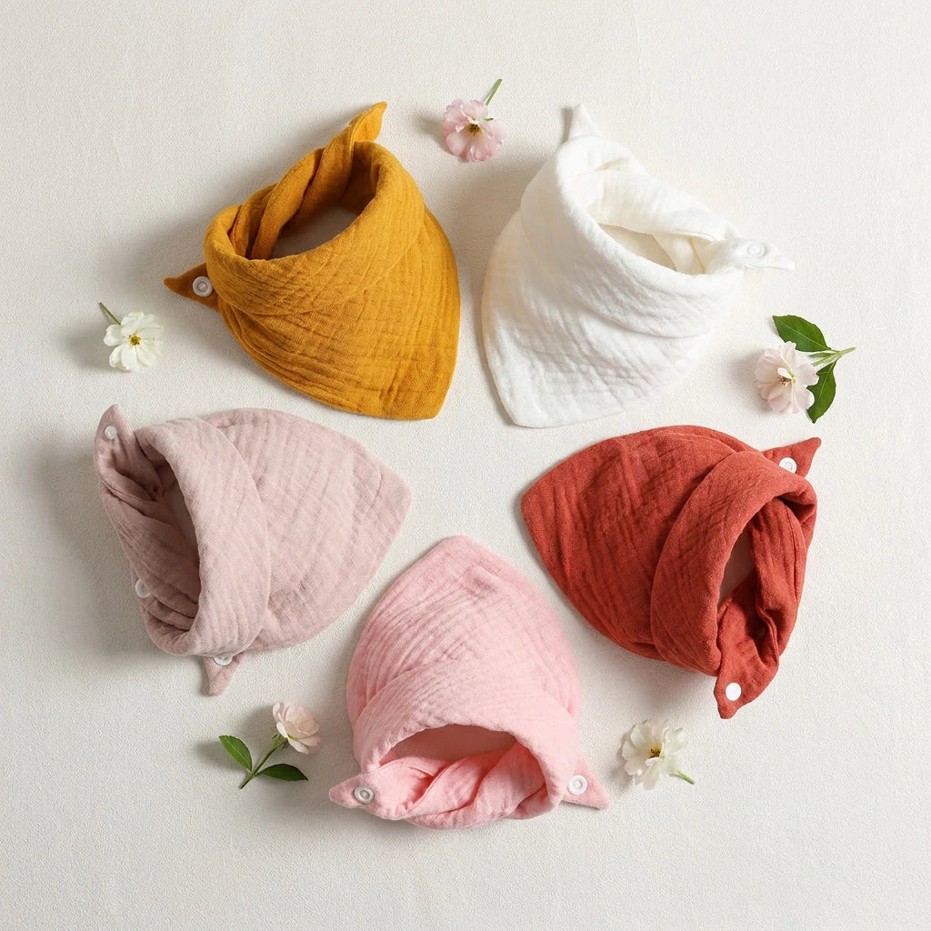 Five soft cotton baby bibs in mustard, white, terracotta, and two shades of pink, with snap closures.