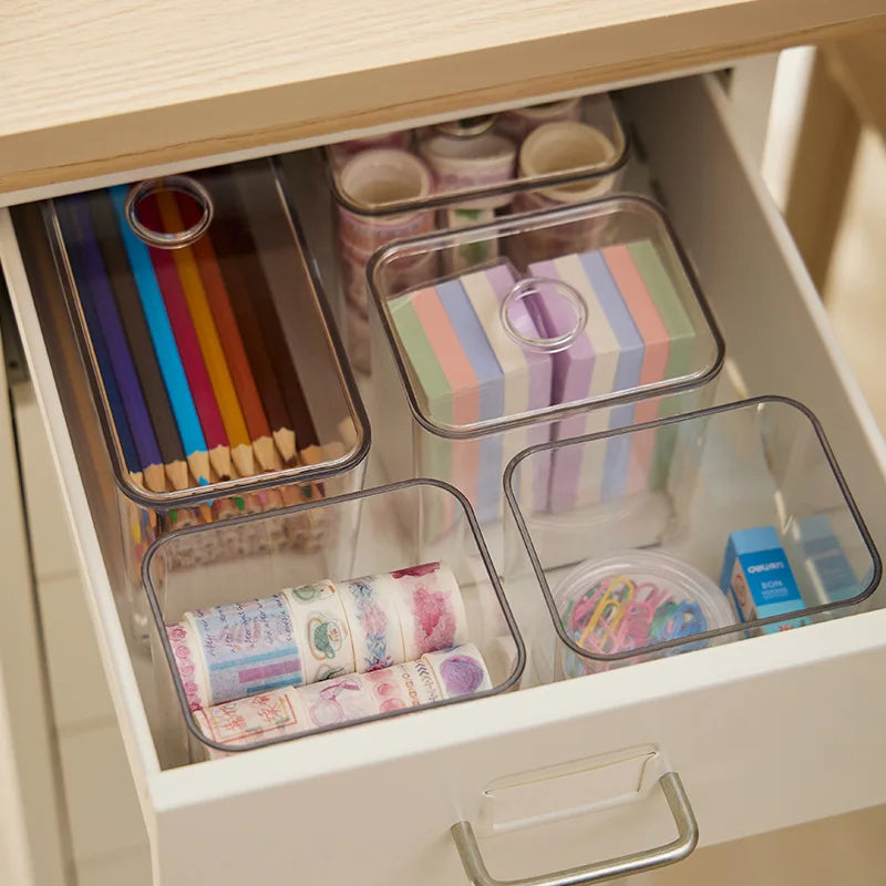 Clear acrylic drawer organizers holding pencils, sticky notes, washi tape, and paper clips.