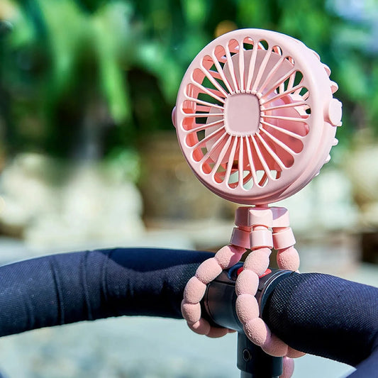 Pink portable rechargeable stroller fan with flexible tripod legs attached to a black stroller handle.