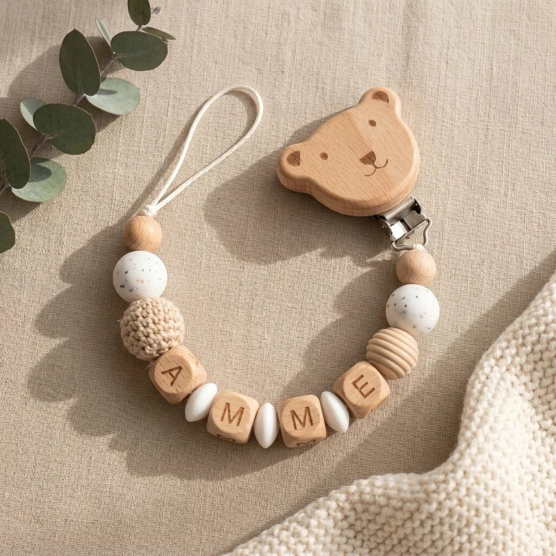 Personalized wooden and silicone pacifier clip with bear design and "AMME" name.