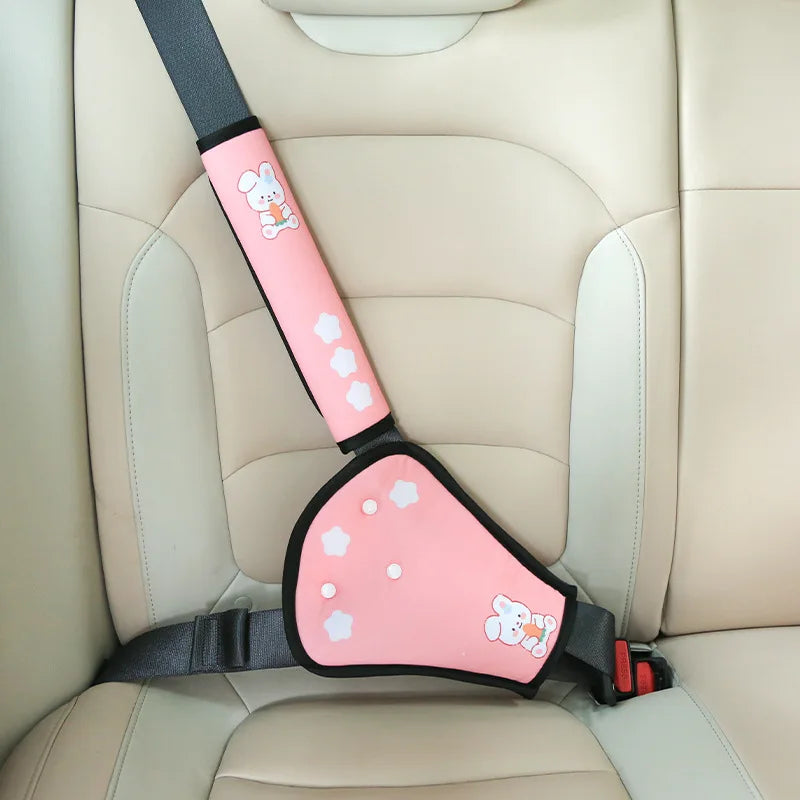 Pink child car seat belt adjuster with cute bunny and star designs on a beige car seat.