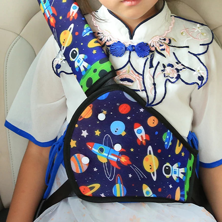 Child wearing a blue space-themed car seat belt adjuster and shoulder pad for comfort and safety.
