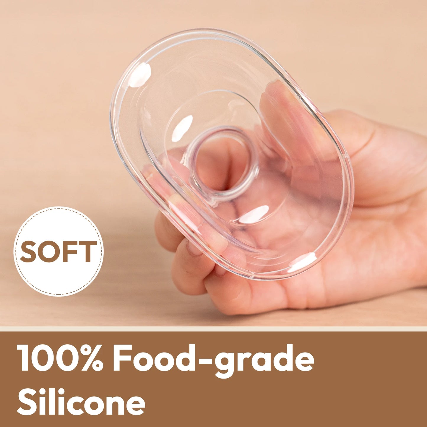 Hand holding a clear, soft, 100% food-grade silicone breast pump flange.