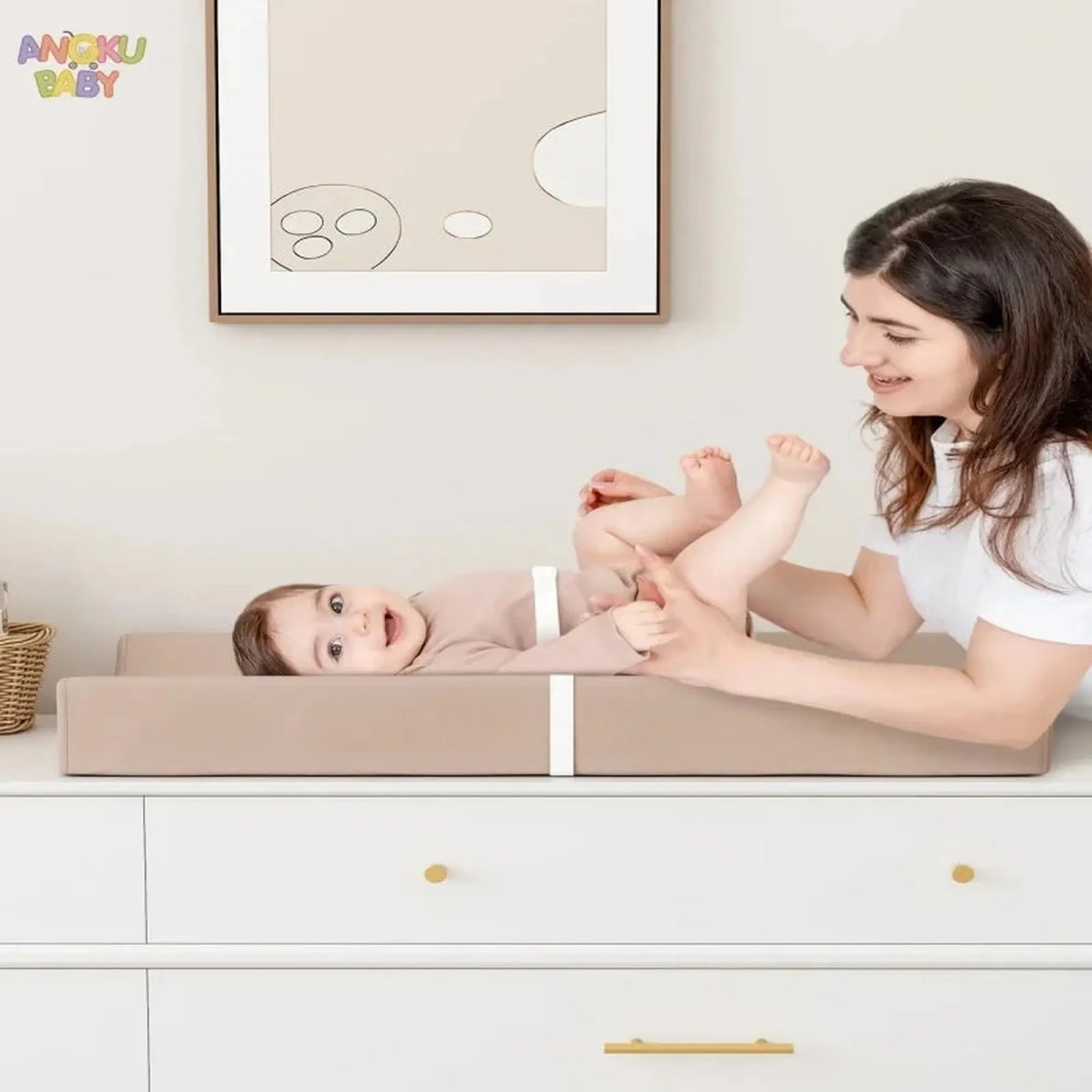 Orthopedic waterproof baby changing pad with safety belt, beige faux leather, on a white dresser.