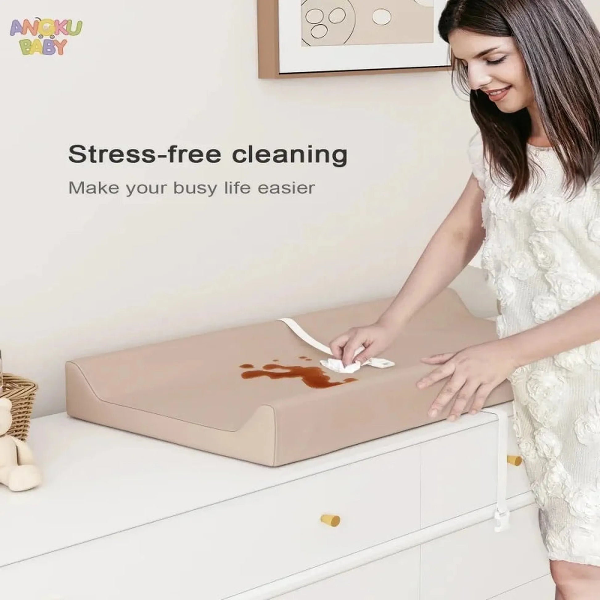 Woman cleaning a beige waterproof orthopedic baby changing pad with a white cloth.