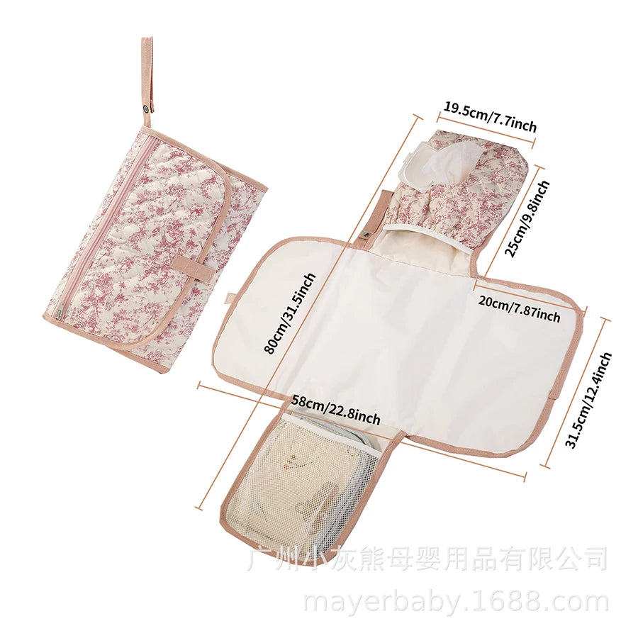 Pink floral quilted portable changing pad with storage pockets, shown open with dimensions and folded.