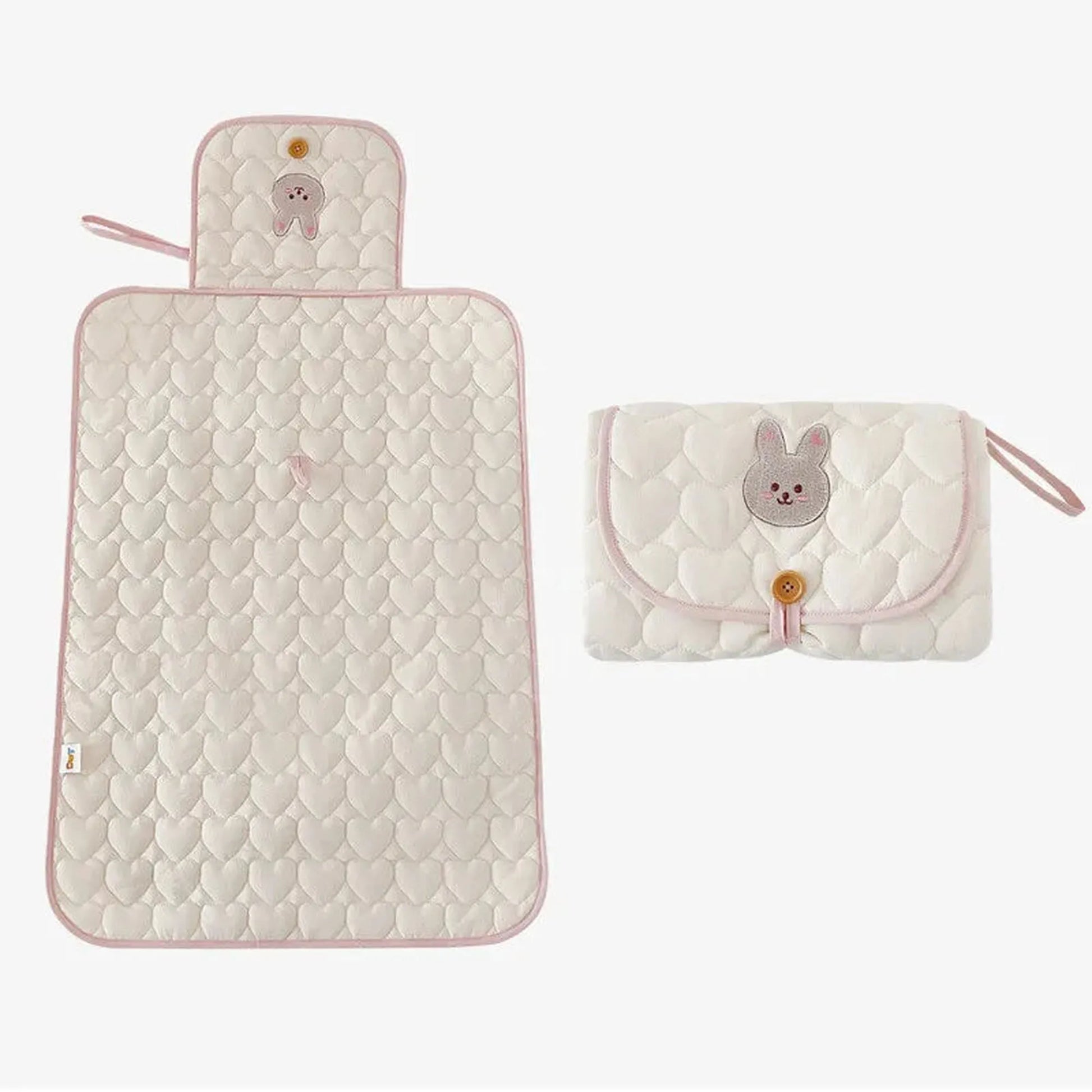 Portable quilted white cotton changing pad with pink trim and bunny embroidery, shown open and folded.