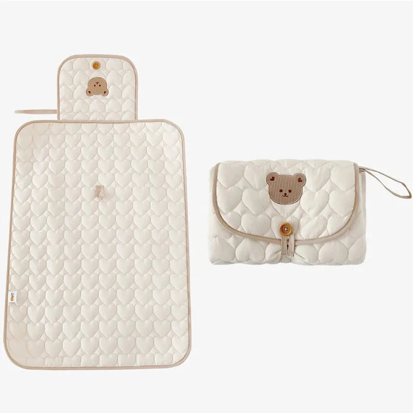 Portable, foldable, water-resistant cotton baby changing mat in cream with heart quilting and a bear design.
