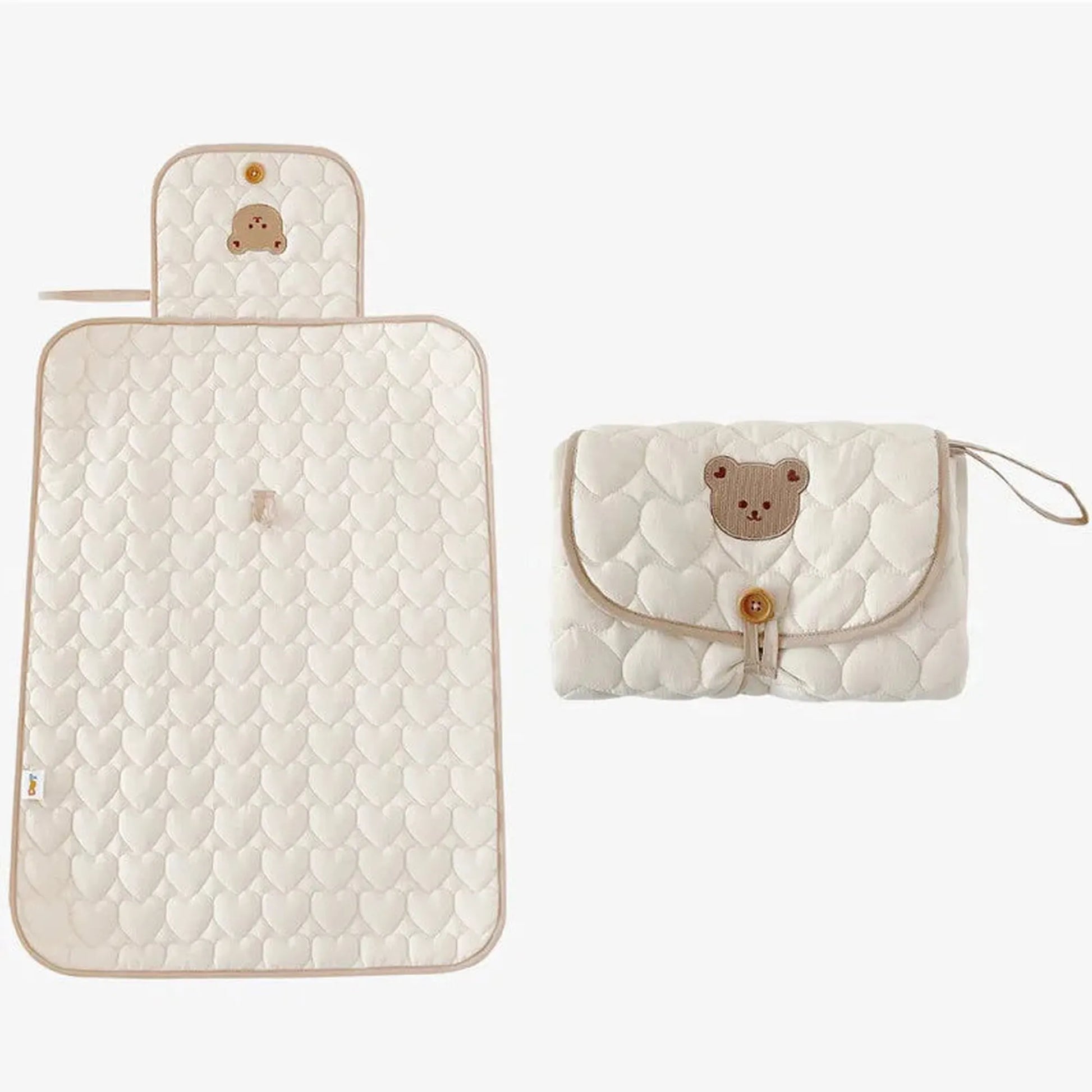 Portable, foldable, water-resistant cotton baby changing mat in cream with heart quilting and a bear design.