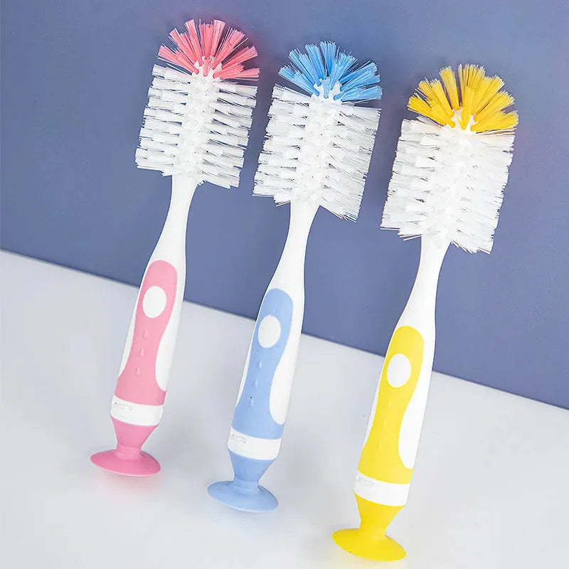 Three colorful 2-in-1 baby bottle and nipple cleaning brushes with vacuum bases in pink, blue, and yellow.