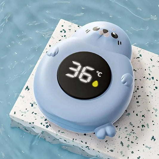 Light blue seal-shaped digital baby bath thermometer floating in water, displaying "36°C" and a yellow indicator.