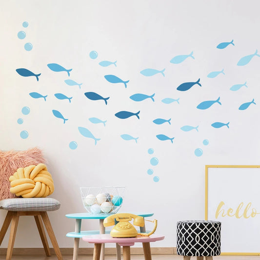 Blue sea fish and bubble wall decals decorating a child's white room with colorful furniture.