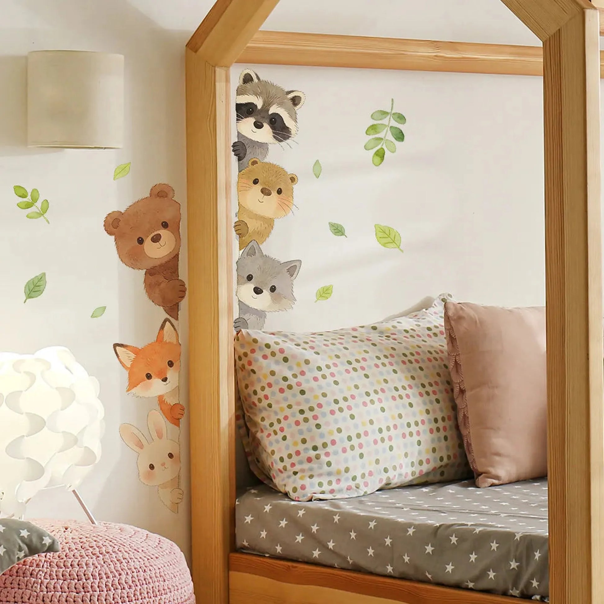 Forest animal wall decals for nursery, featuring a raccoon, bear, otter, wolf, fox, and bunny peeking from a bed frame.