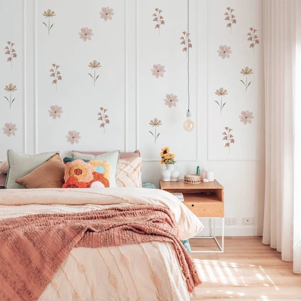 Watercolor flower wall decals in pink and beige on a white bedroom wall above a bed.
