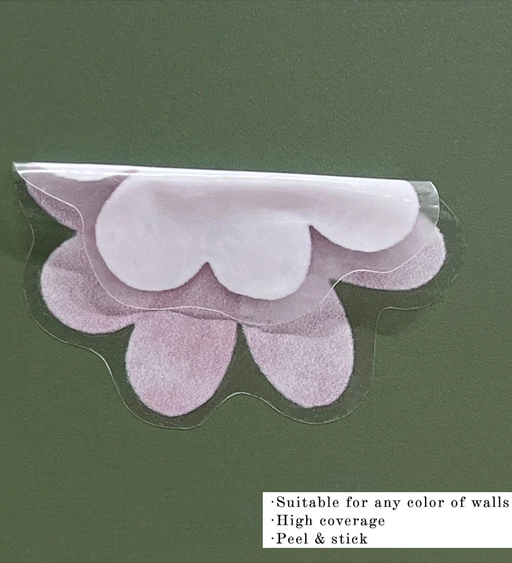 Pink watercolor flower wall decal being peeled from its backing on a green wall.