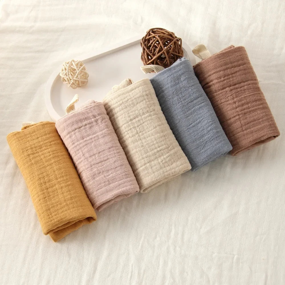 Soft, multi-colored 100% cotton gauze baby towels in mustard, pink, cream, blue, and brown.