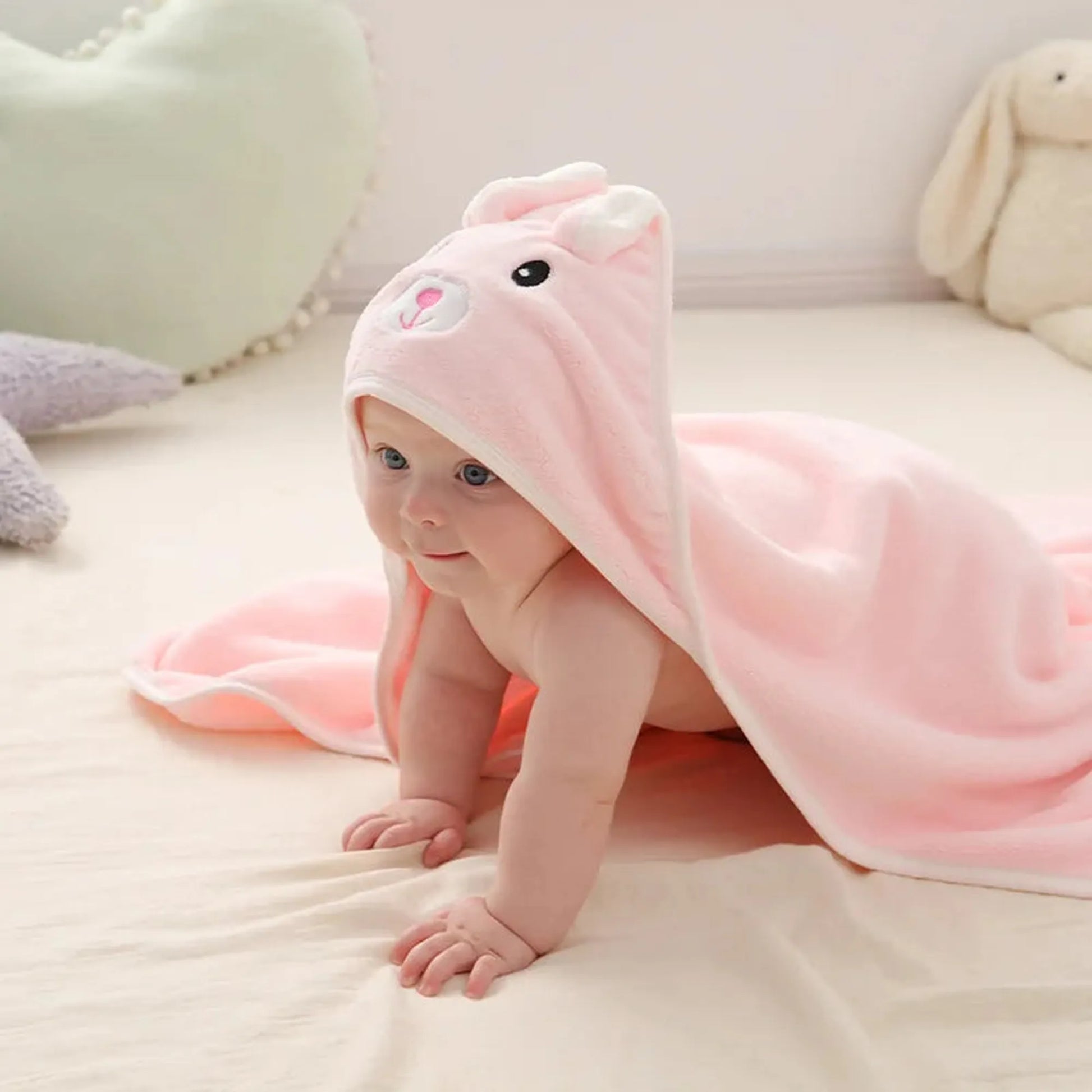 Pink coral fleece baby hooded towel with cute bunny ears and face, covering a crawling infant.