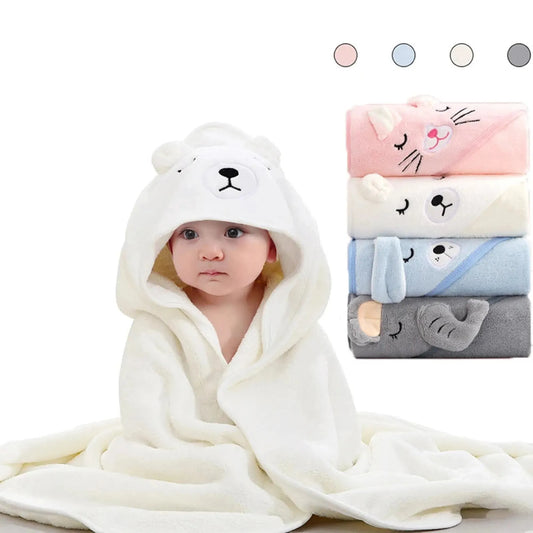 Baby in a soft white coral fleece hooded towel with a bear face, next to stacked animal-design towels in pink, white, blue, and gray.