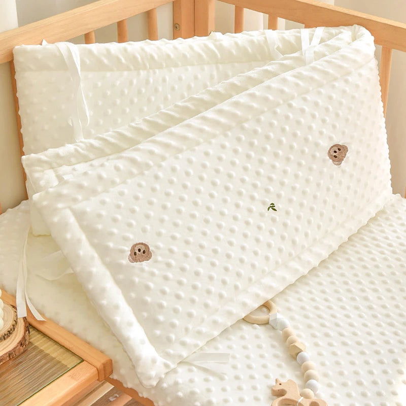 Soft white polyester crib bumper with cute cartoon animal embroidery and textured dots.