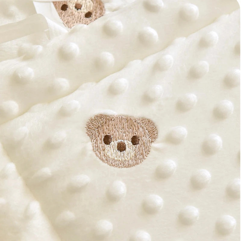 Soft cream polyester crib bumper with raised dots and embroidered brown teddy bear faces.