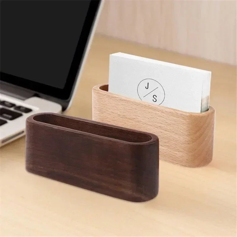 Minimalist wooden business card holder in light and dark wood, oval design, on a desk.