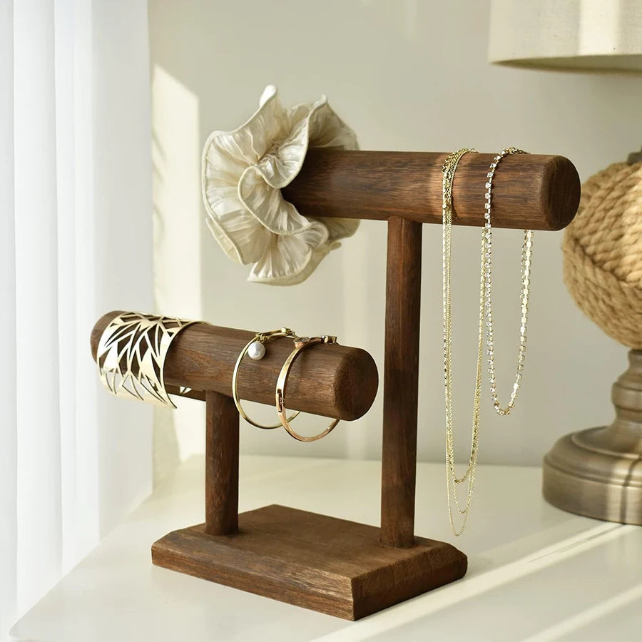 Dark wood T-bar jewelry organizer stand displaying bracelets, necklaces, and a scrunchie.
