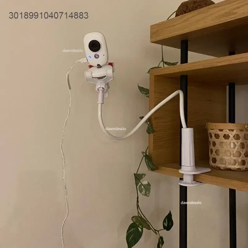 White flexible baby monitor arm with clamp, attached to a wooden shelf, holding a white monitor.