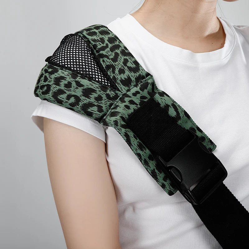 Green leopard print ergonomic baby carrier with wide shoulder strap and buckle.