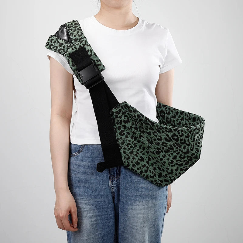 Woman wearing a green leopard print ergonomic baby carrier with a wide shoulder strap and buckle.