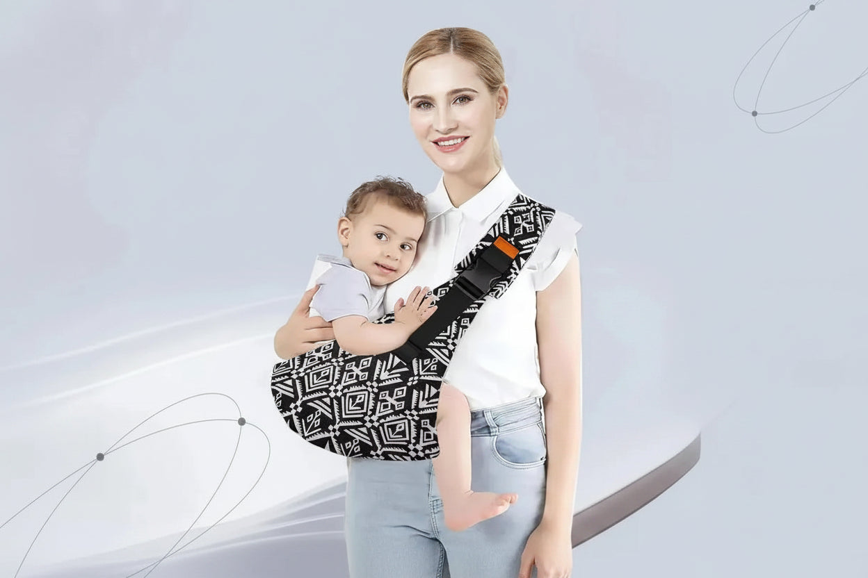 Woman smiling, wearing a black and white geometric pattern cotton crossbody baby carrier with an orange buckle, holding a baby.