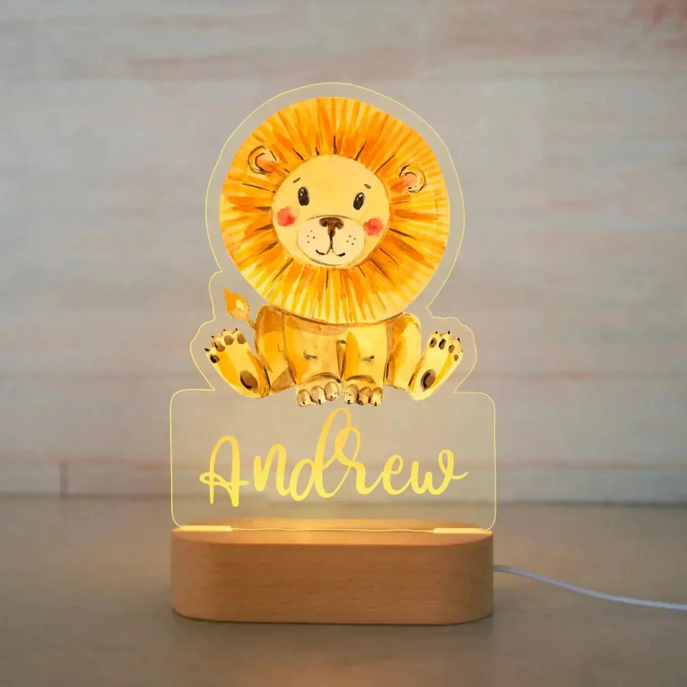 Personalized LED night light with a cute lion design on clear acrylic and a wooden base, customized with the name "Andrew.