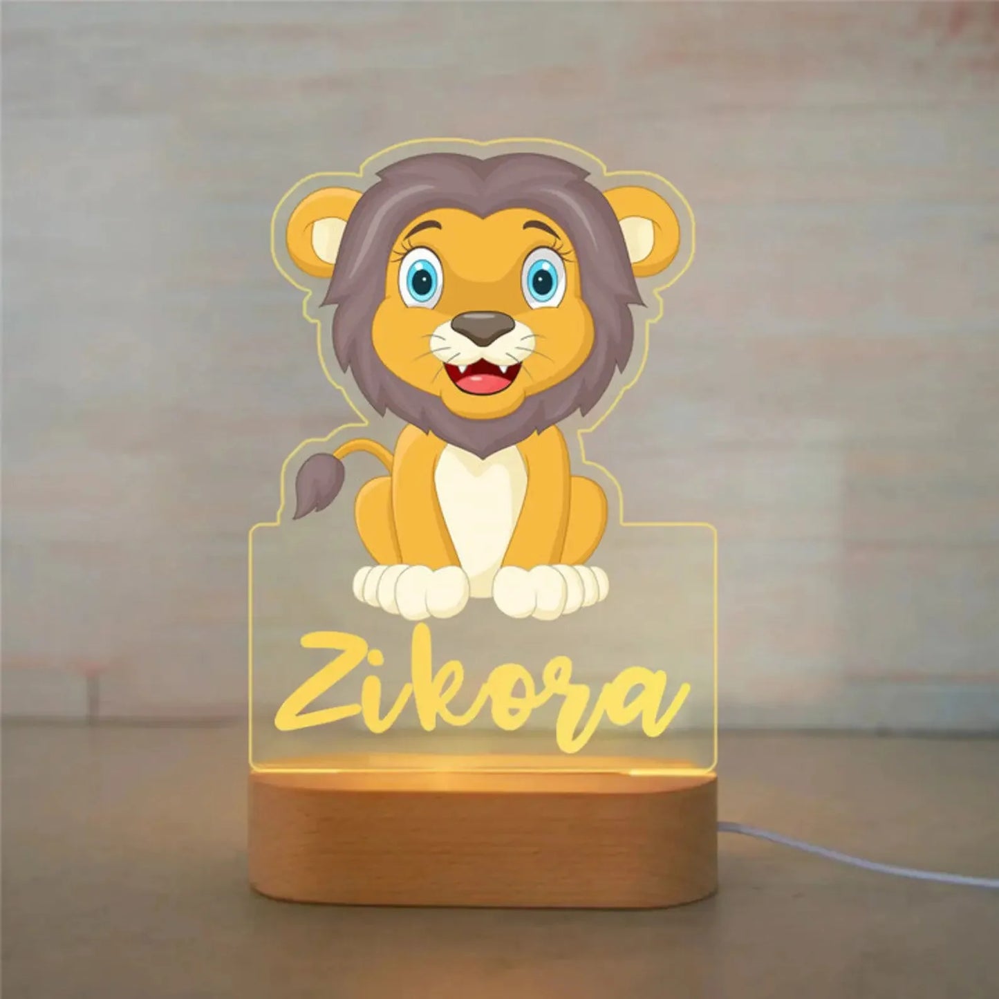Personalized LED night light with a cute lion design on acrylic and a wooden base, customized with the name "Zikora".