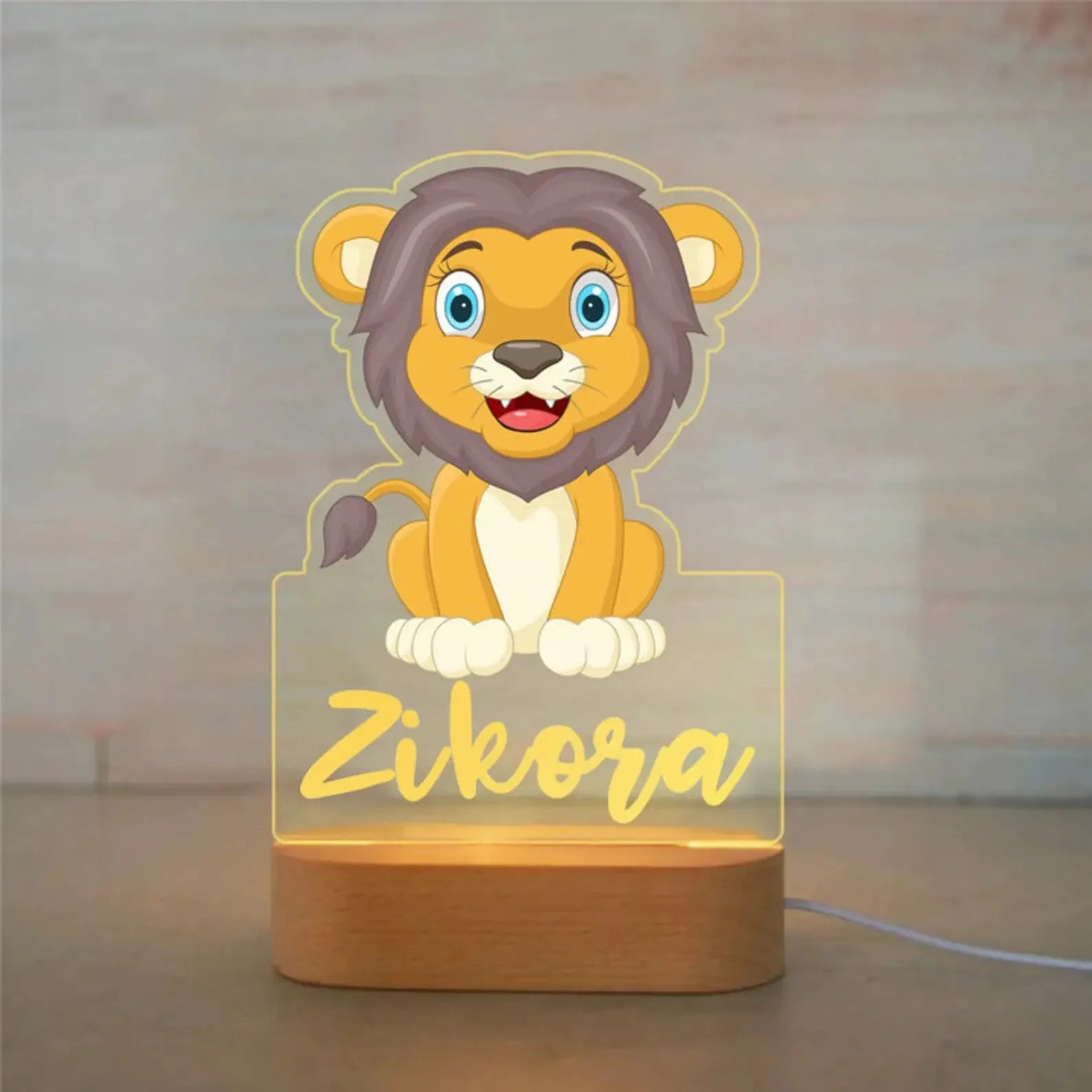 Personalized LED night light with a cute lion design on acrylic and a wooden base, customized with the name "Zikora".