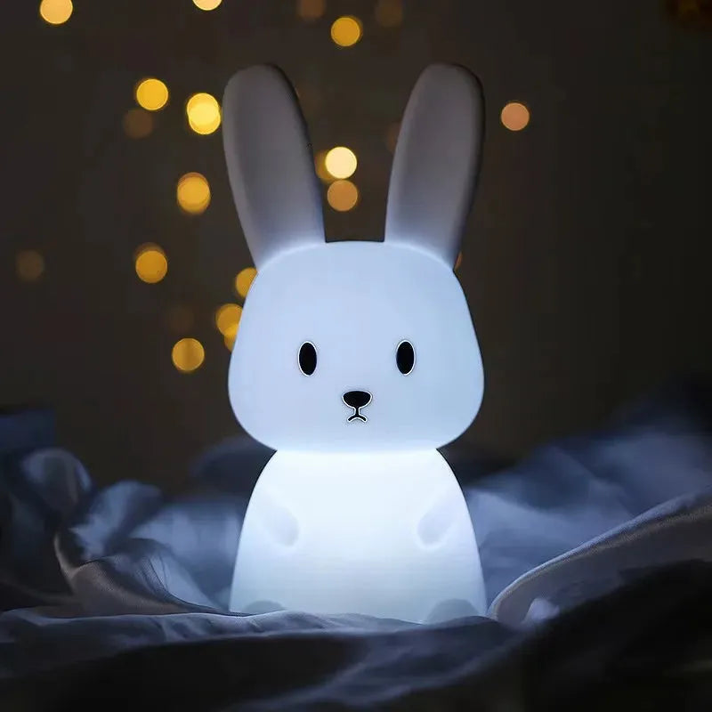 White silicone rabbit night light with touch sensor, glowing softly in a dark room.