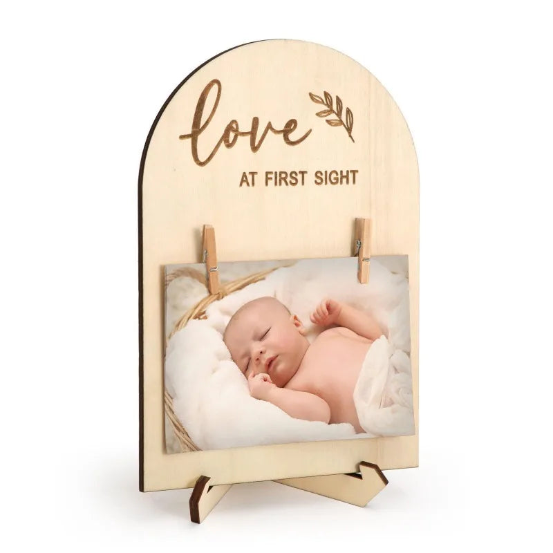 Natural wood arch photo frame with "love at first sight" engraving, holding a baby photo with mini clips.