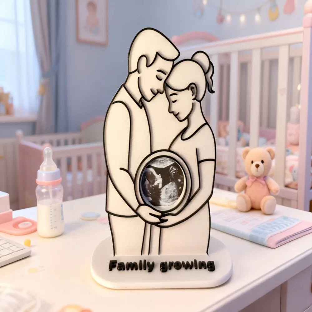 White plastic ultrasound photo frame with "Family growing" text, featuring a couple embracing a baby scan.