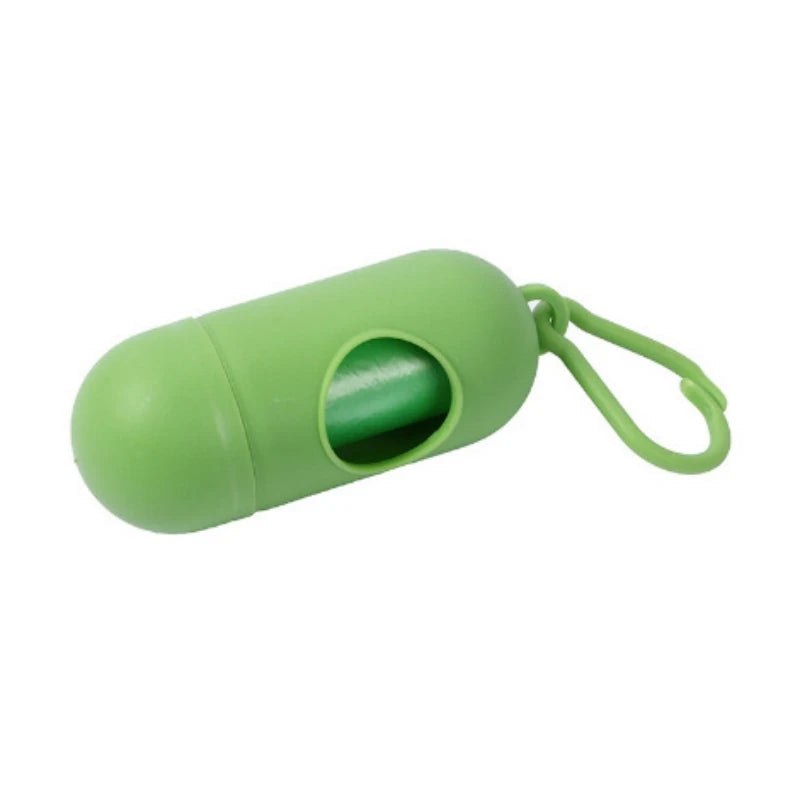 Green capsule-shaped portable waste bag dispenser with a roll of bags and a clip.