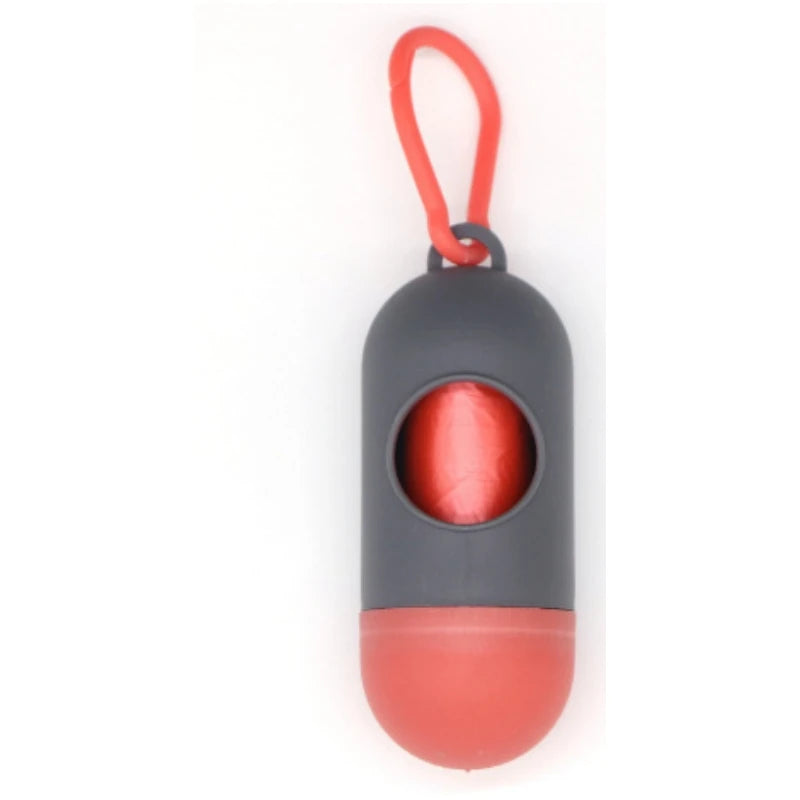 Compact gray and red capsule-shaped portable waste bag dispenser with a red loop for easy attachment.
