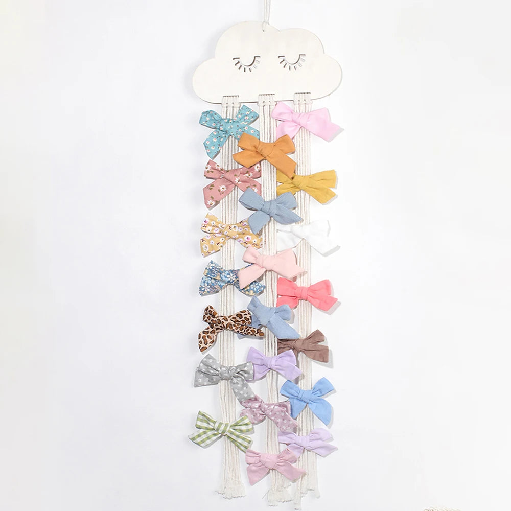 White wooden cloud wall hanger with macrame strings displaying colorful fabric hair bows.