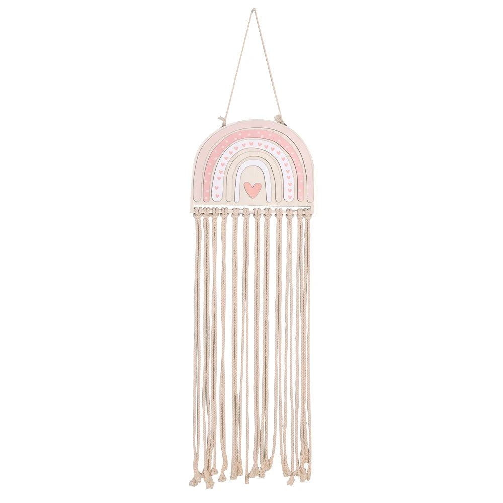 Pink wooden rainbow wall organizer with macrame fringe for girls' hair accessories.