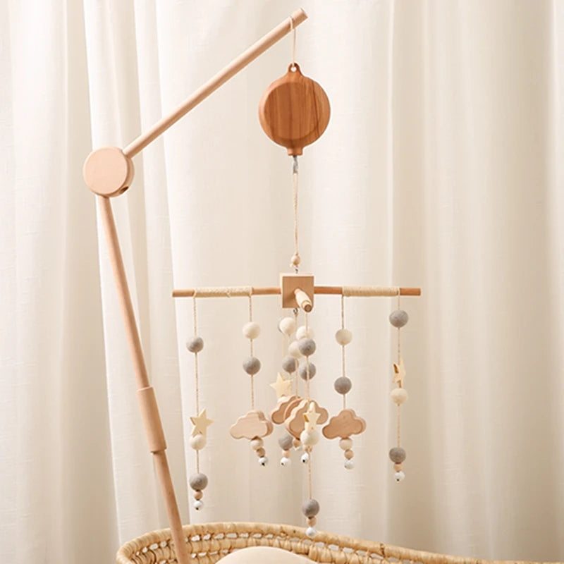 Nordic wooden musical crib mobile with felt balls, clouds, and stars in natural tones.