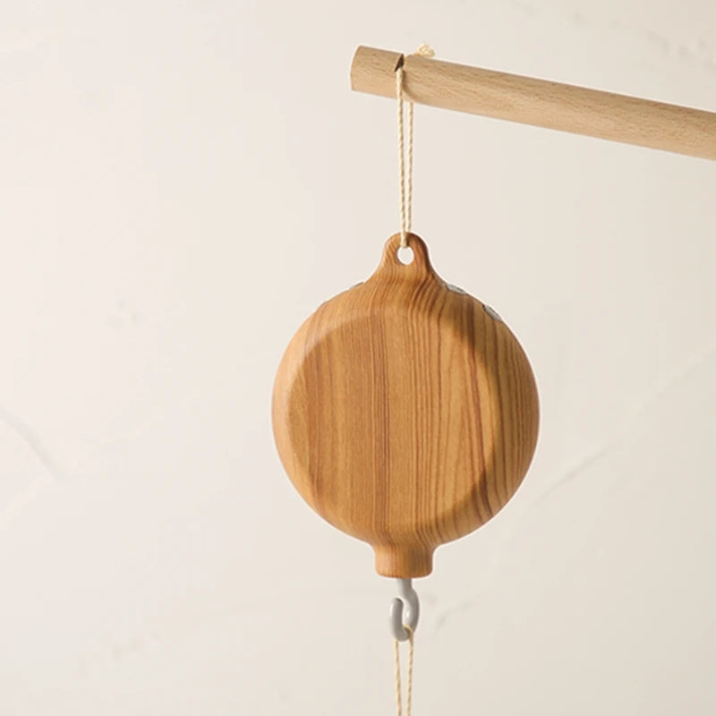 Nordic style wooden musical crib mobile with natural wood grain, hanging from a light wood rod.