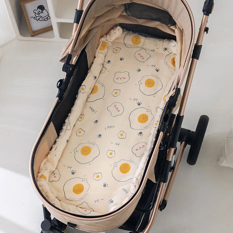 Soft beige baby stroller cushion with a playful fried egg and paw print pattern.