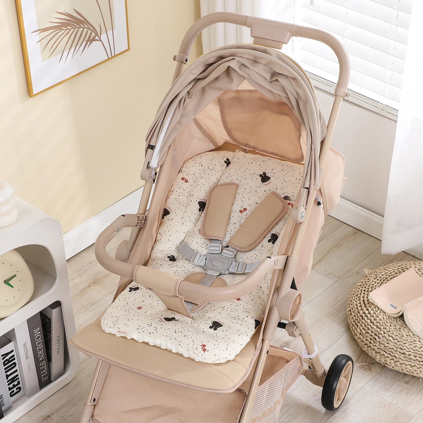 Beige baby stroller with a soft, patterned cotton-polyester seat cushion and safety harness.